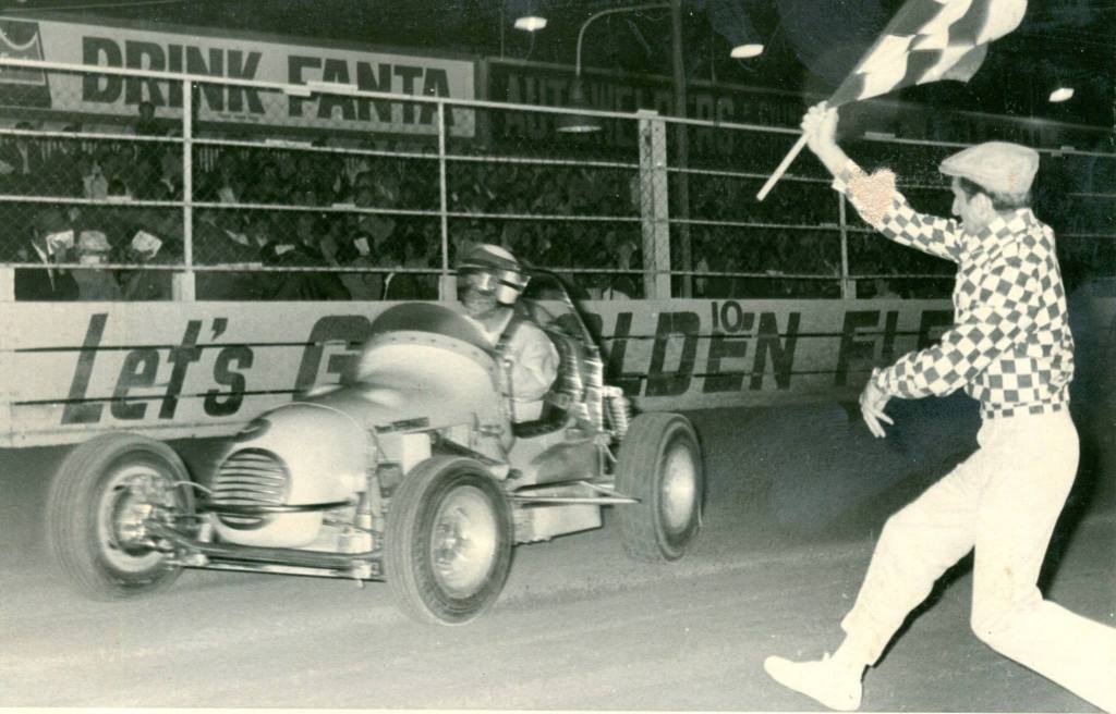 Photo thanks to 'Down Memory Lane With Noel O'Connor'. Driver Bob Wente takes the chequered flag at Rowley Park Speedway. And is that a young Glen Dix